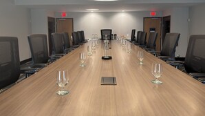 A conference room with a long table, chairs, and wine glasses.