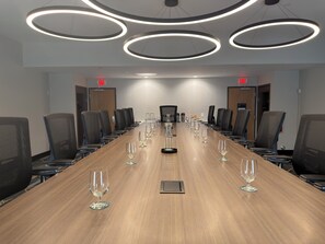 A conference room with a long table, chairs, and wine glasses.