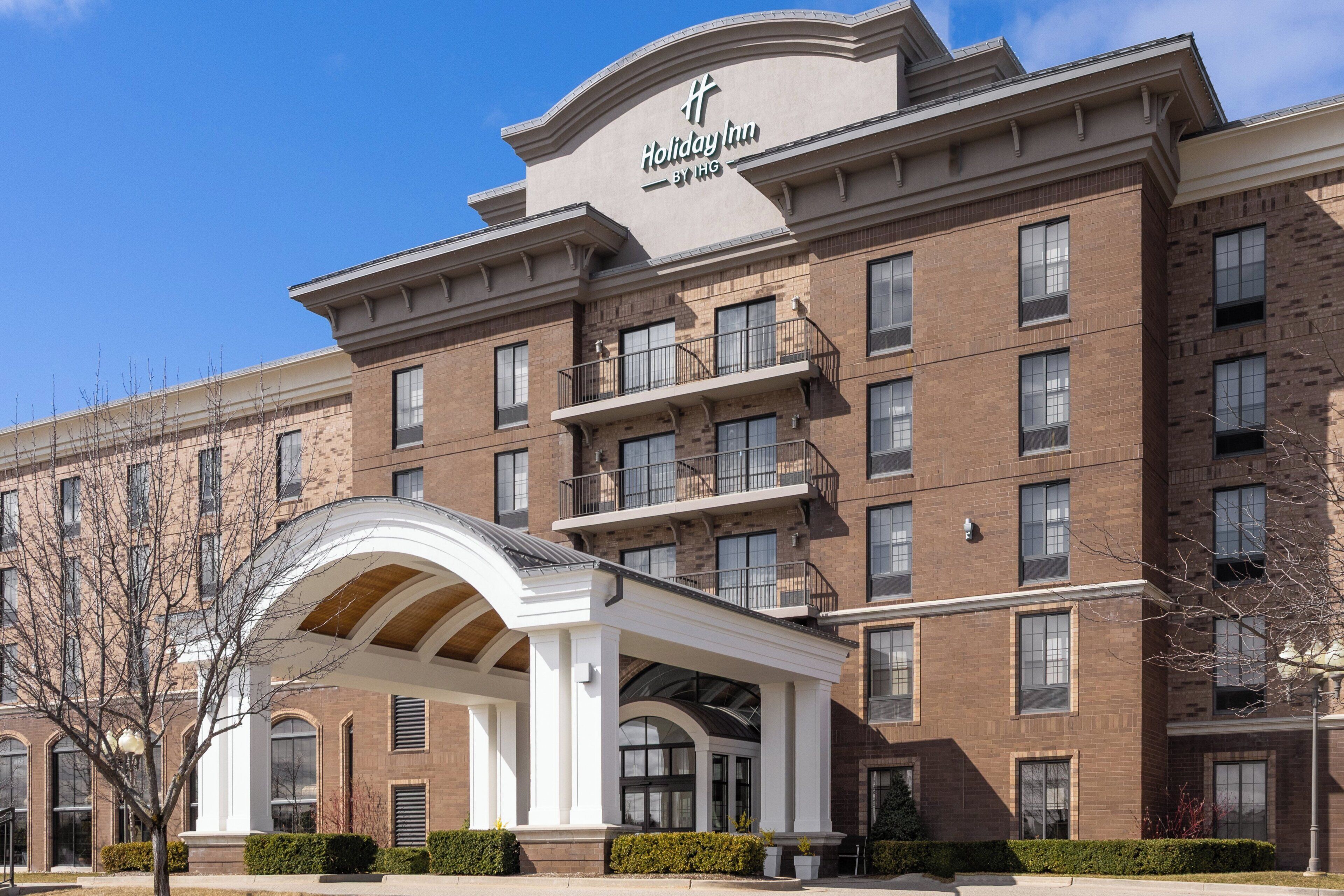 A multi-story Holiday Inn by IHG building with a prominent entrance, large windows, and a brick facade.