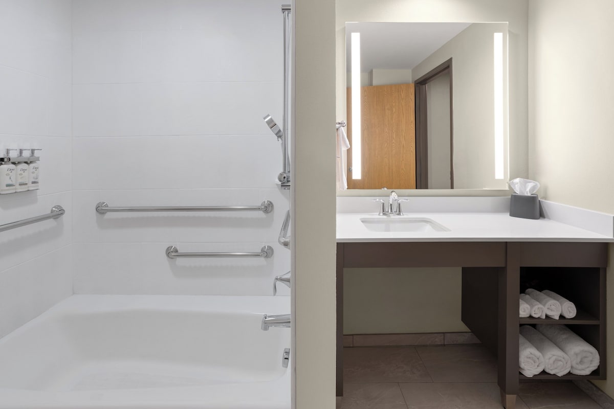 A bathroom with a bathtub, a shower, a sink, and a mirror.