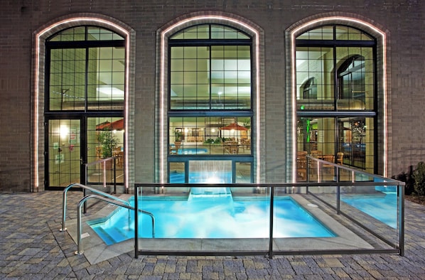 A building with three large arched windows, a glass-enclosed pool area, and outdoor seating visible through the windows.