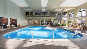 Une piscine intérieure dotée d’une mezzanine, entourée d’espaces de détente et de plantes en pot.
