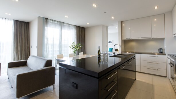 A modern kitchen with a central island, stainless steel appliances, and white cabinetry. - Quest Carlaw Park (Auckland)