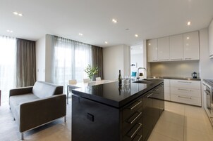 A modern kitchen with a central island, stainless steel appliances, and white cabinetry.