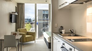 A modern hotel room with a balcony, a kitchenette, a dining area, and a bed. - Quest Carlaw Park (Auckland)