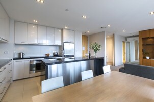 A modern kitchen with stainless steel appliances, a central island with seating, and a dining area with a large table.