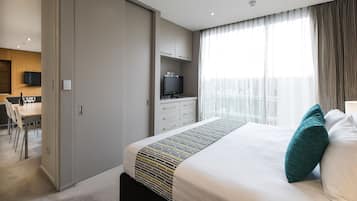 Una habitación de hotel con cama, televisor, escritorio y zona de comedor.