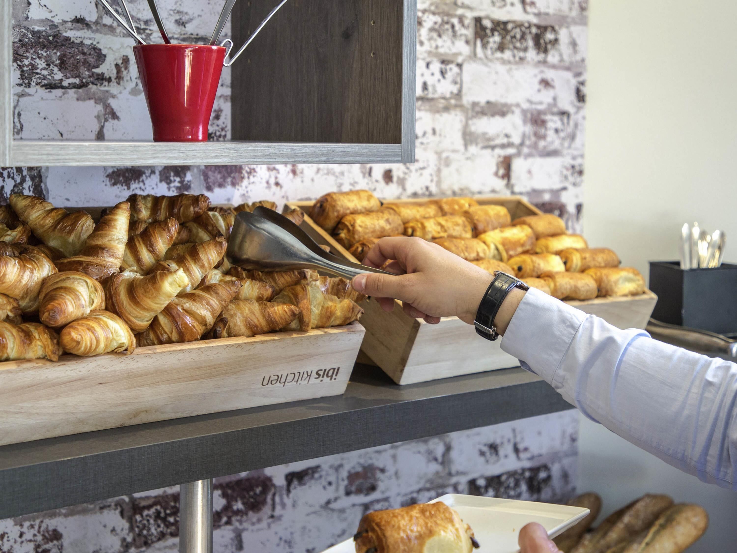 Un buffet garni de diverses pâtisseries, une tasse rouge et une pancarte en bois.