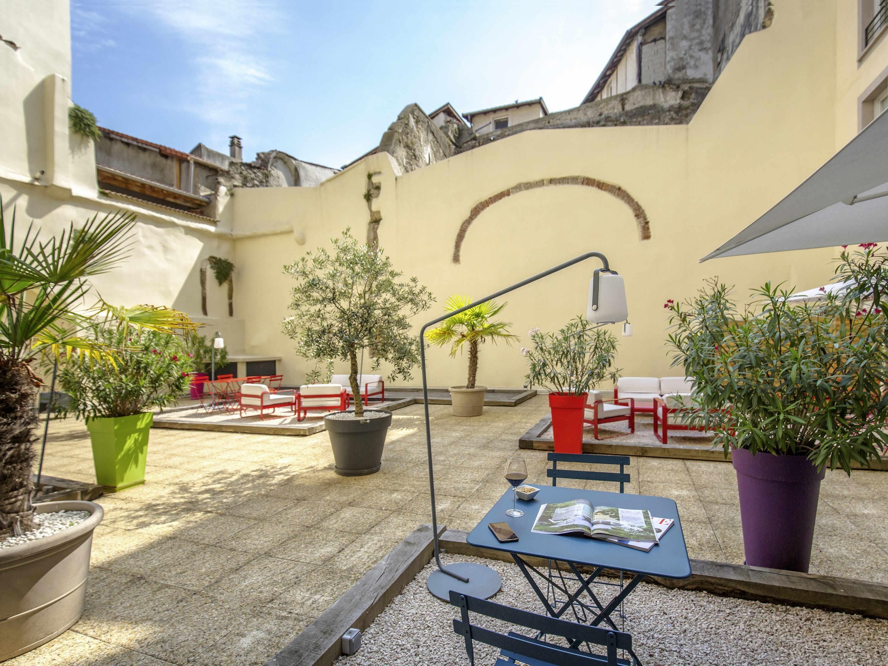 An outdoor seating area with tables, chairs, and potted plants.