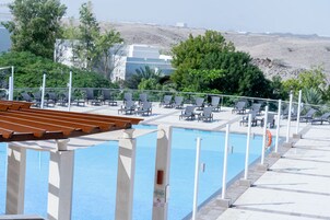 A poolside area with lounge chairs and a wooden deck.