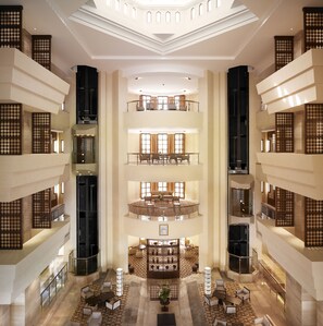 A multi-level hotel lobby with a central atrium, multiple seating areas, and a grand staircase. - Crowne Plaza Sohar by IHG (Sohar)
