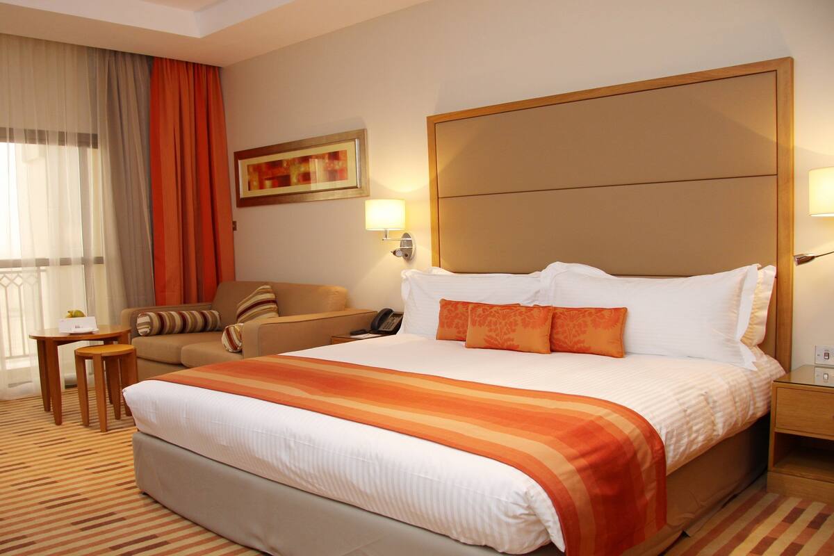 Una habitación de hotel con una cama grande, un sofá, una mesita y una silla.