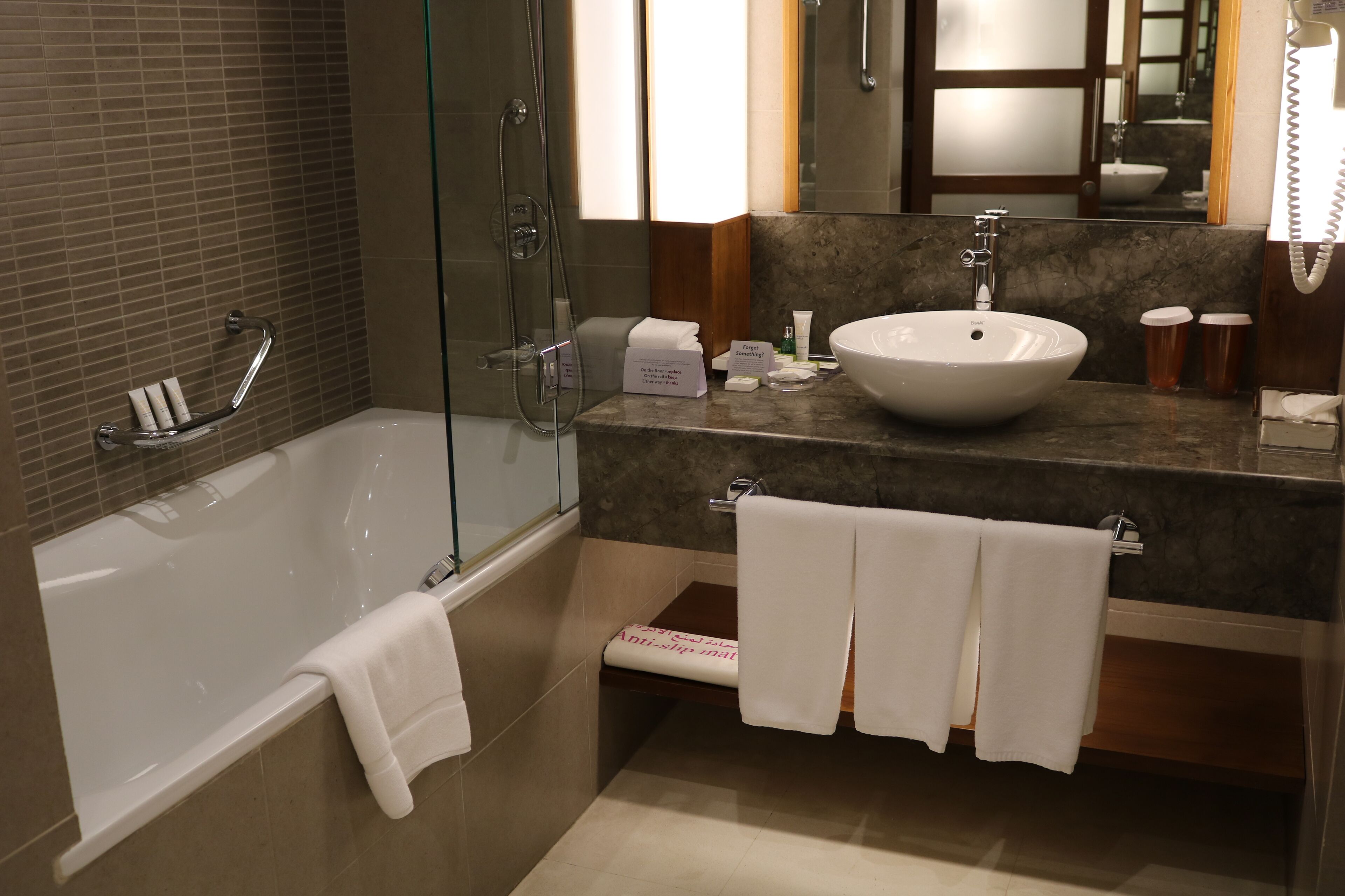 A modern bathroom with a glass-enclosed shower, a white sink, and a marble countertop.