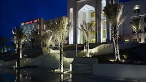 A modern hotel with a prominent entrance, palm trees, and a pool area. - Crowne Plaza Sohar by IHG (Sohar)