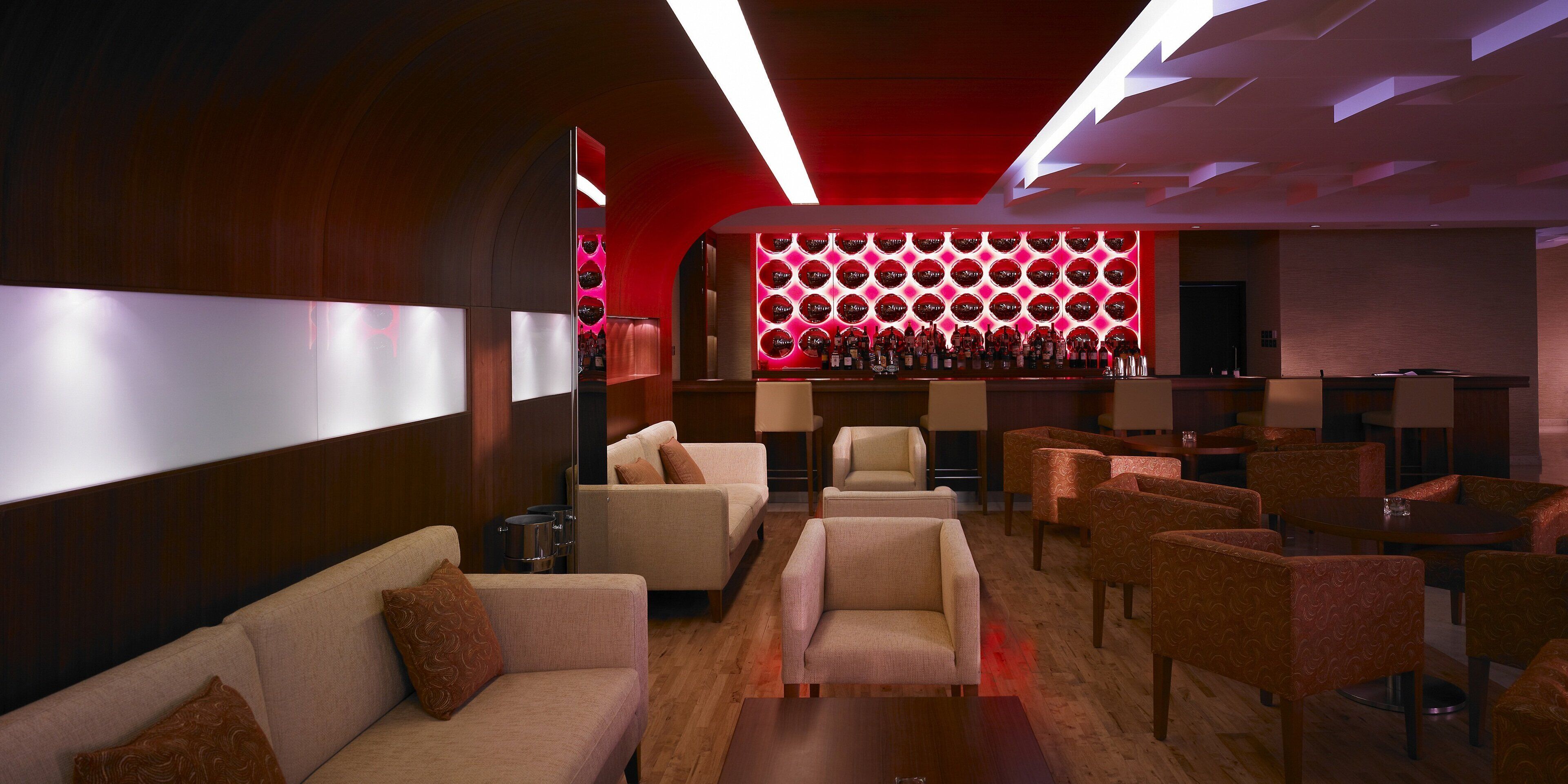 Een moderne lounge met banken, fauteuils en een bar met een opvallend rond lichtobject.