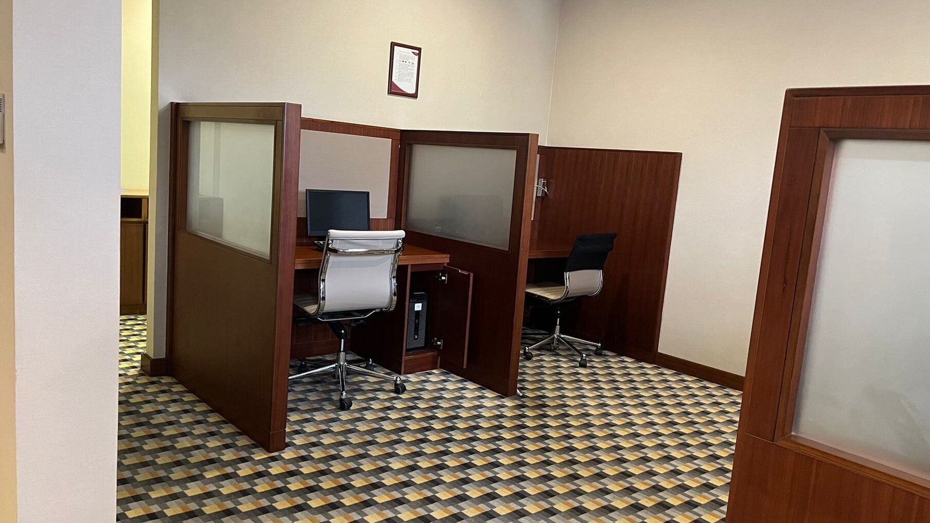 Ein Zimmer mit Schachbrettmuster-Boden, Holzwänden und Bürostühlen.