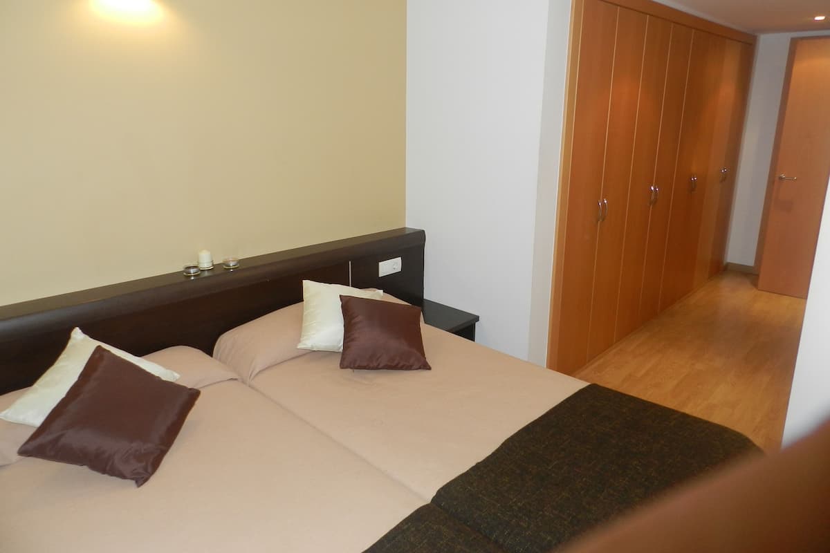 A hotel room with a bed, bedside table, and a wardrobe.