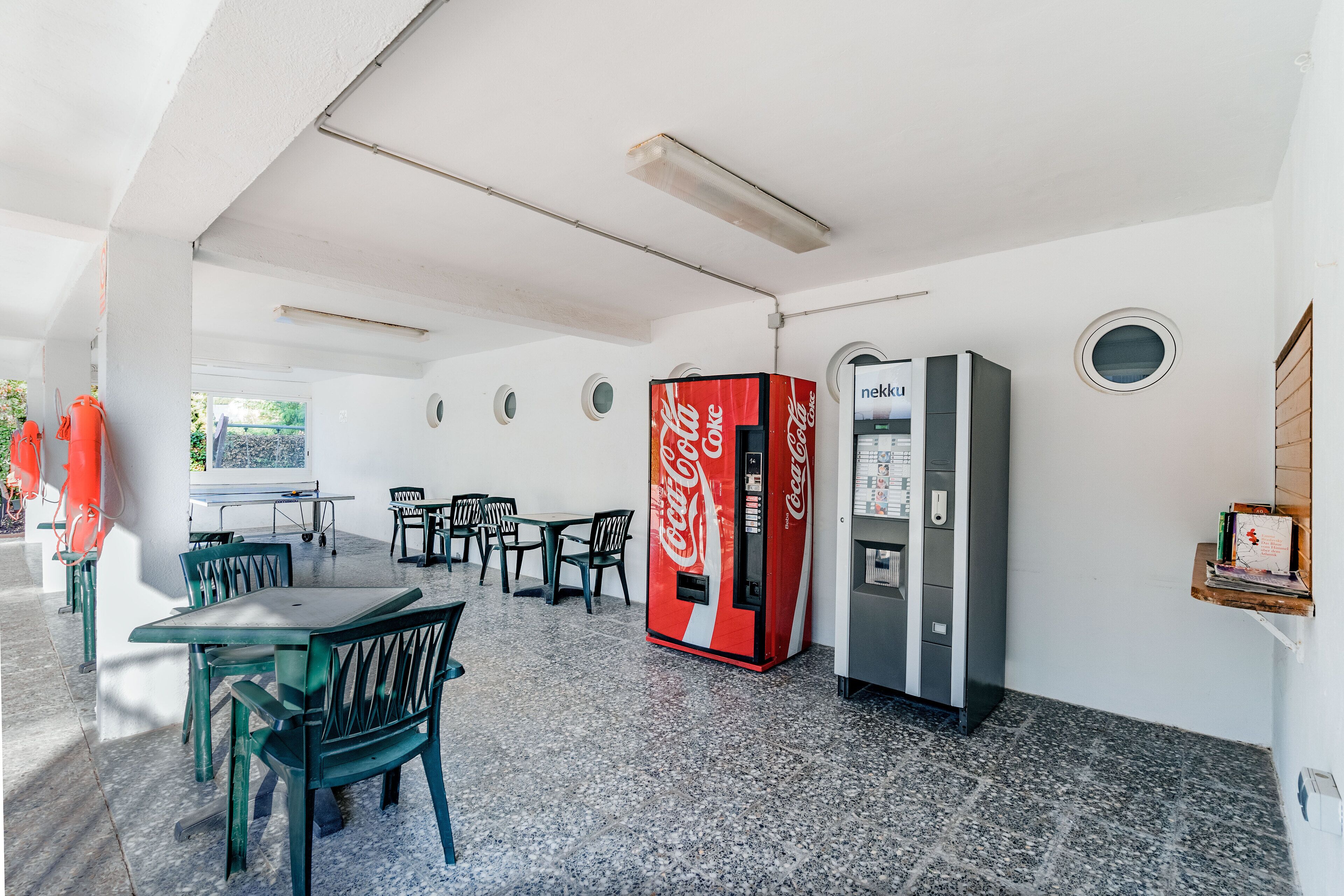 Et værelse med spiseplads, en Coca-Cola automat og en automat med Nescafe logo.