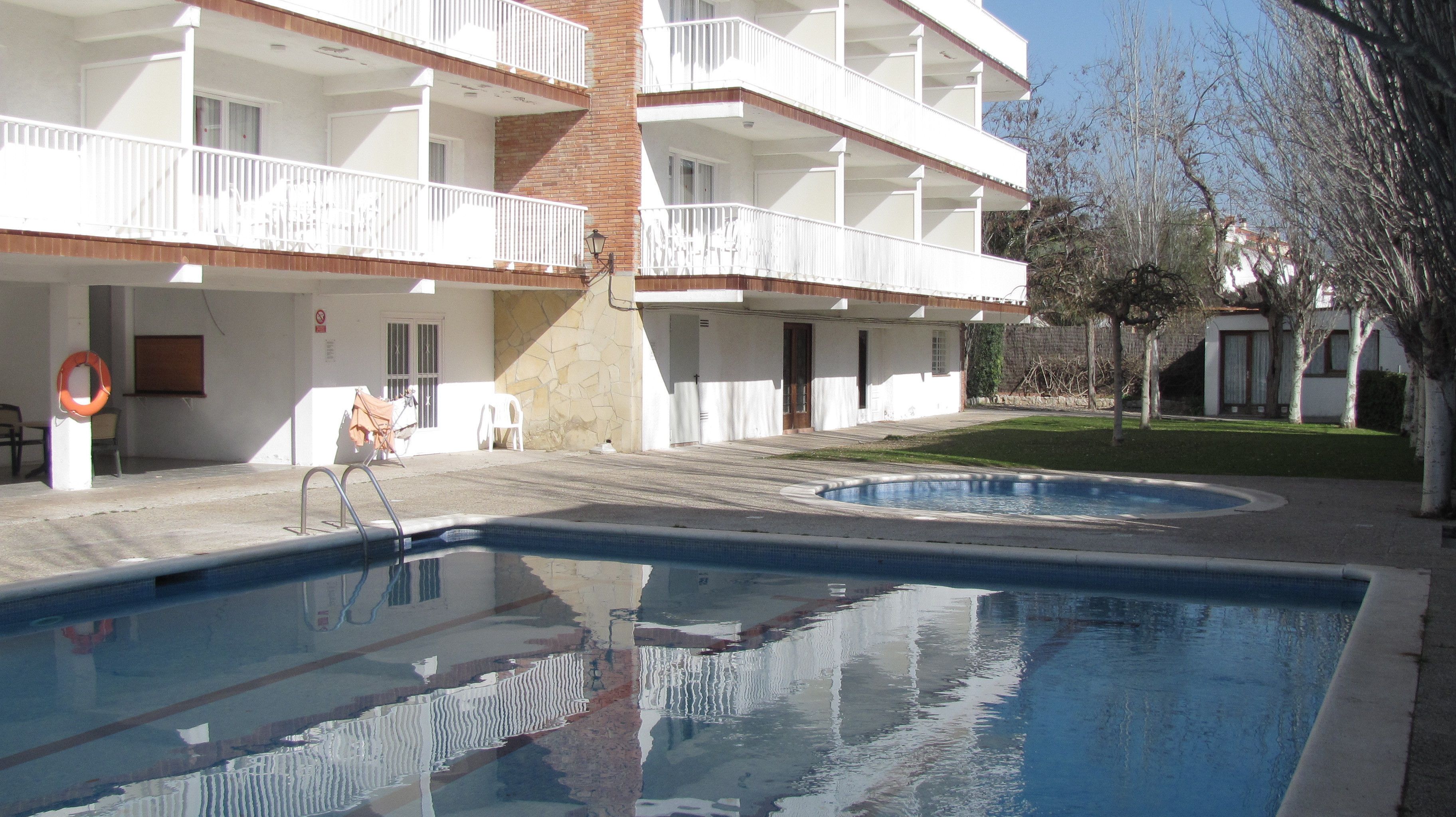 Een hotel met een zwembad, een overdekt terras en een gevel van baksteen.