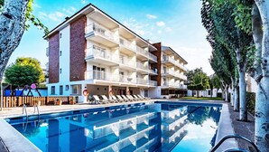 Un hotel de varios pisos con piscina, mobiliario exterior y fachada de ladrillo.