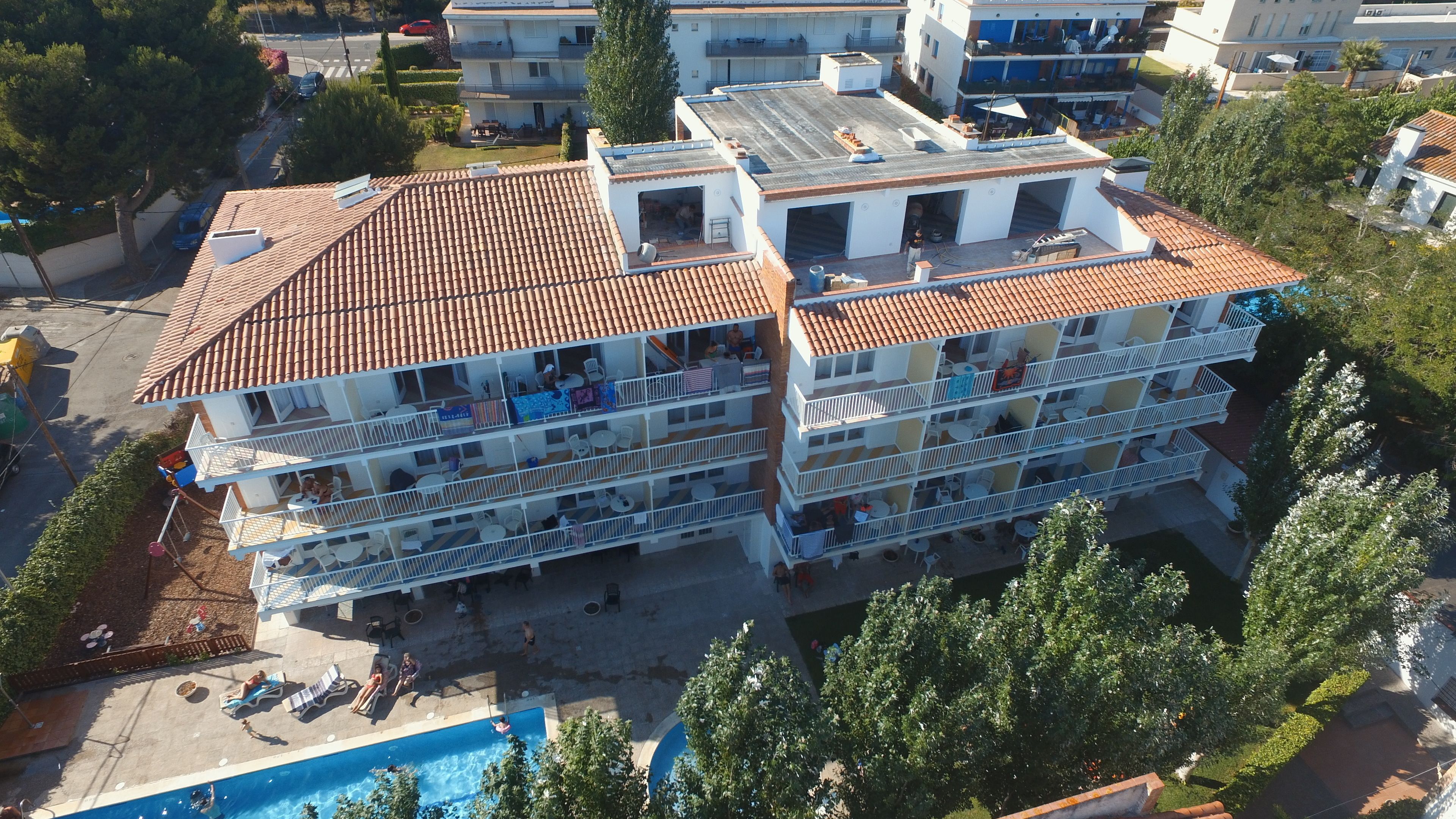 A multi-story building with balconies, a swimming pool, and a rooftop terrace.