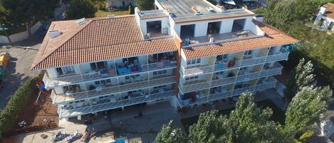 A multi-story building with balconies, a swimming pool, and a rooftop terrace.