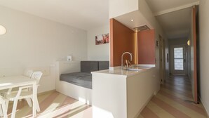 Un espacio habitable moderno y funcional, con kitchenette, comedor y una pequeña zona de estar.