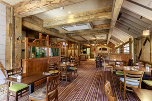 A rustic interior with wooden beams, a striped floor, and a variety of seating arrangements including tables and benches. - The Victoria Hotel (Canterbury)