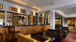 A bar area with wooden paneling, seating, and a variety of bottles and glasses. - The Victoria Hotel (Canterbury)