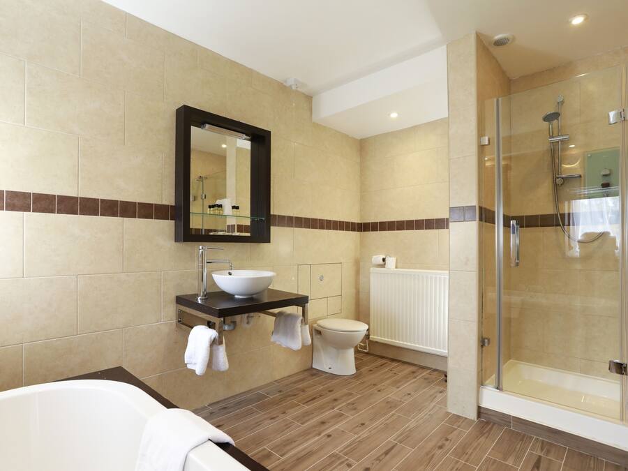 A modern bathroom with a bathtub, a glass-enclosed shower, a sink with a mirror, and a toilet.