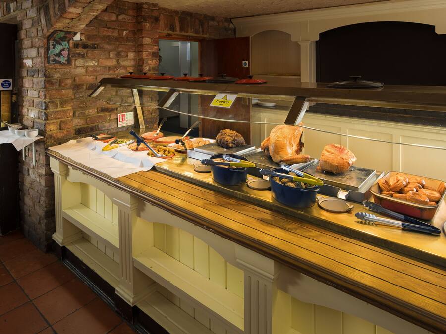 A buffet counter with various food items and utensils.