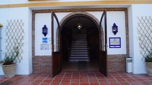 A hotel entrance with a brick archway, tiled stairs, and two lanterns. - Hotel Caserio de Iznajar (Iznajar)