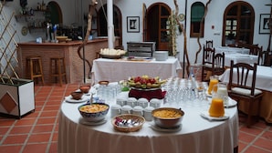 Un comedor con una mesa redonda dispuesta para el desayuno, con tazones de cereal, frutas y vasos.