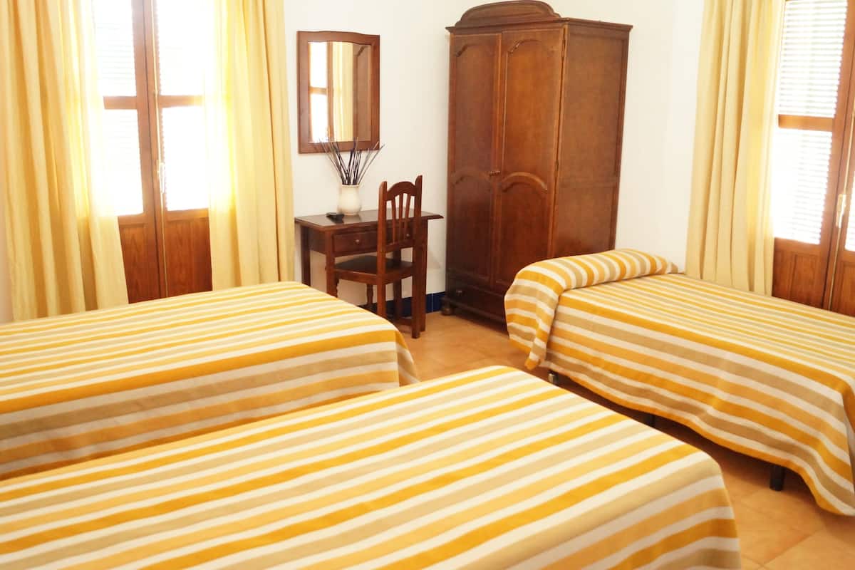 Una habitación con dos camas, un armario de madera, un escritorio y una silla.