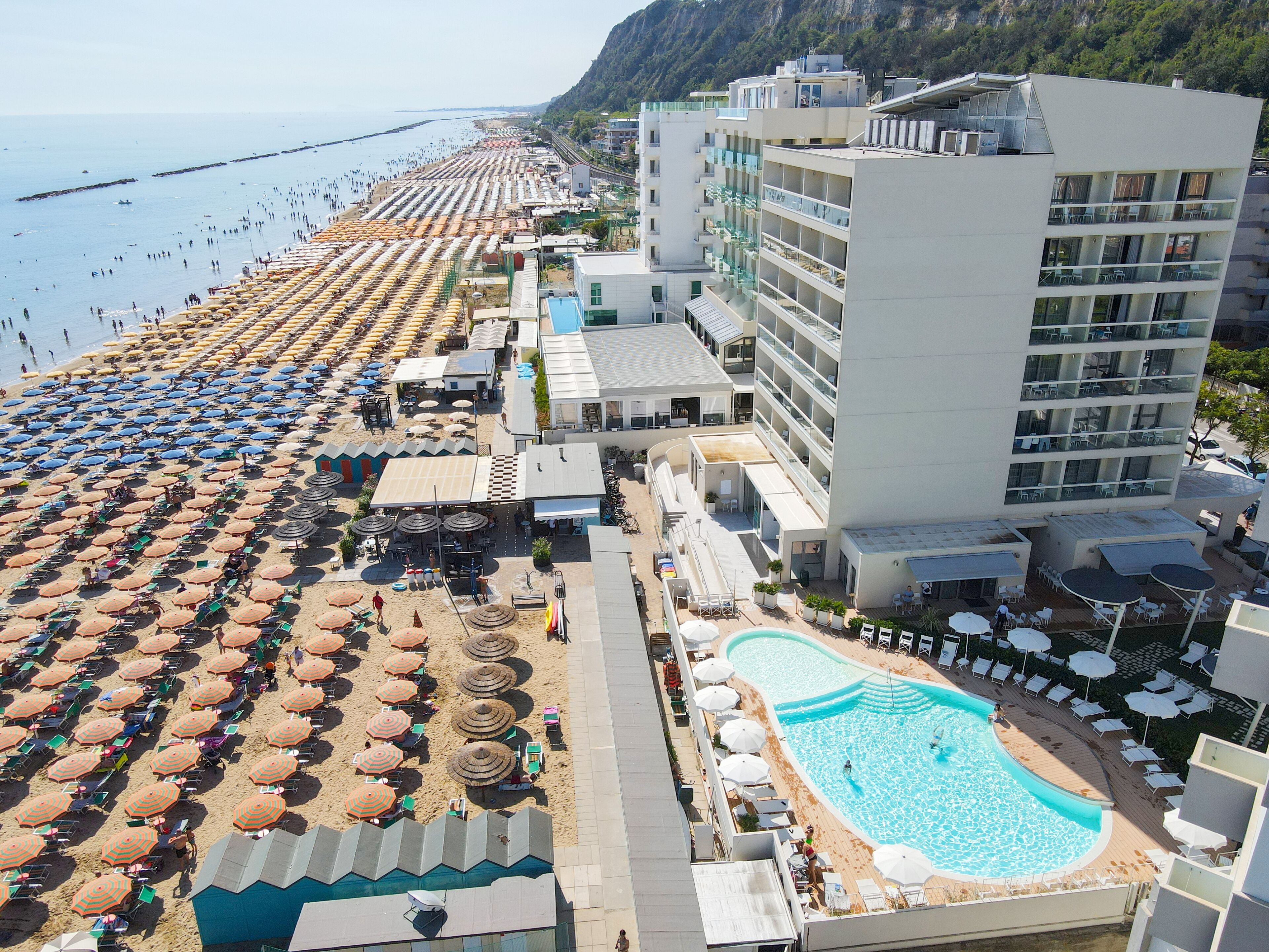 Un complejo turístico con playa, piscina y edificio hotelero.