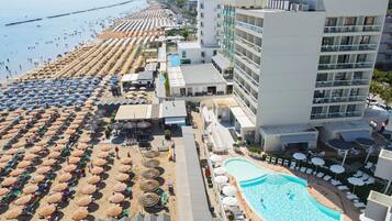 A resort with a beach area, a swimming pool, and a hotel building.