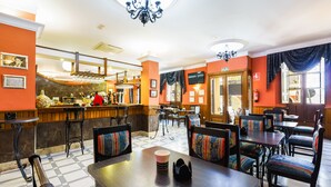 Un restaurante con zona de bar, varias mesas para comer y sillas.