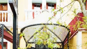 Fachada de hotel roja y blanca, con vestíbulo cubierto y escalera que lleva a la puerta.