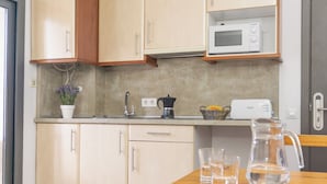 A kitchen with wooden cabinets, a microwave, a coffee maker, and a pitcher on the counter. - RVApartaments Treumal Park (Castell-Platja d'Aro)