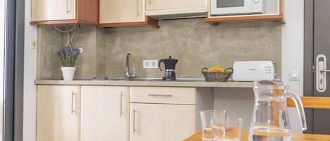 A kitchen with wooden cabinets, a microwave, a coffee maker, and a pitcher on the counter.