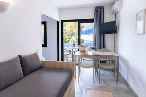 Una sala de estar moderna con un sofá, una mesa de comedor con sillas y un televisor montado en la pared.