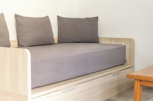 A wooden sofa with a grey cushion and a wooden table beside it.