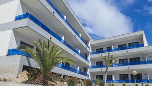 A multi-story hotel with balconies, palm trees, and a clear sky. - RVApartaments Treumal Park (Castell-Platja d'Aro)