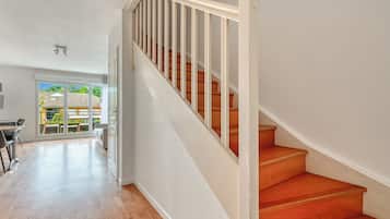 A spacious room with a wooden staircase and a view of a balcony.