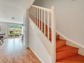 Una habitación amplia con una escalera de madera y vistas a un balcón.