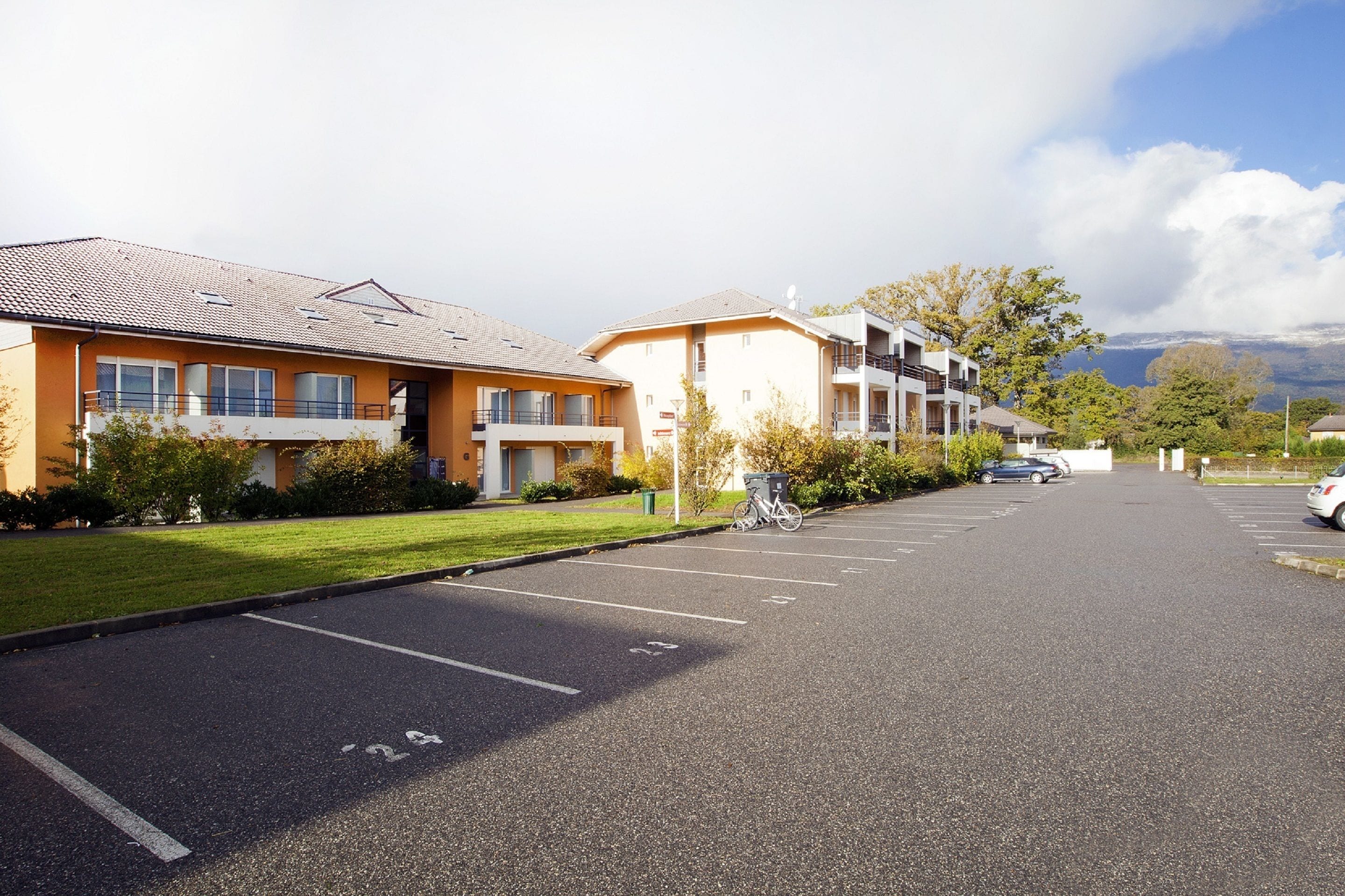 A row of modern buildings with a parking lot in front.