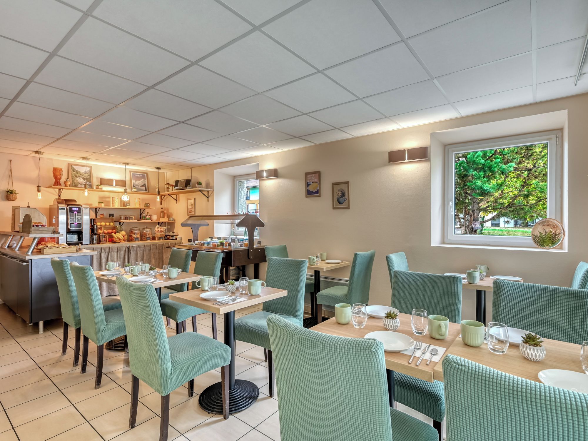 Un restaurante con zona de bar, sillas tapizadas de verde y vista a vegetación a través de una ventana.