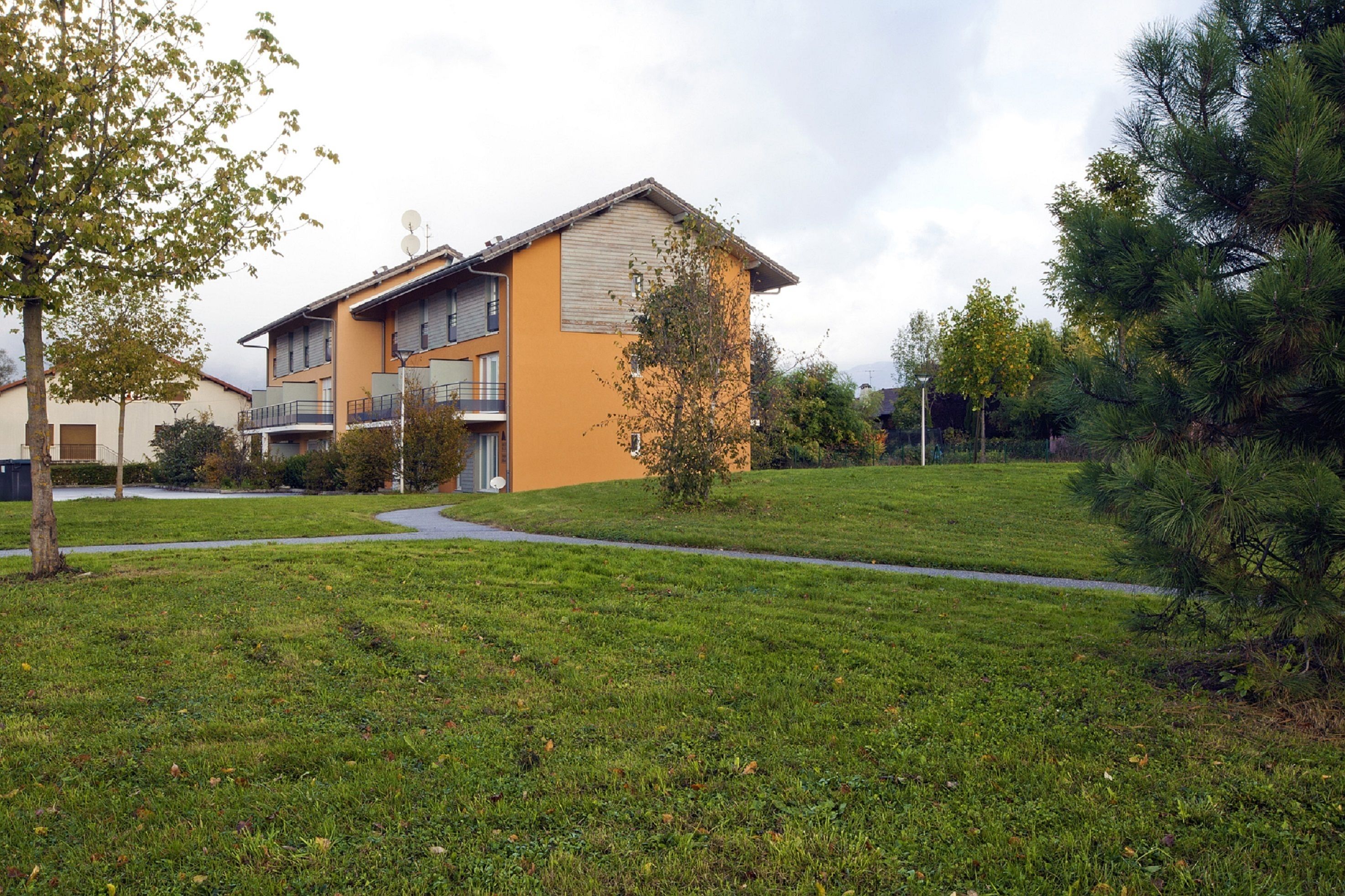 A residential building with a flat roof, multiple balconies, and satellite dishes.