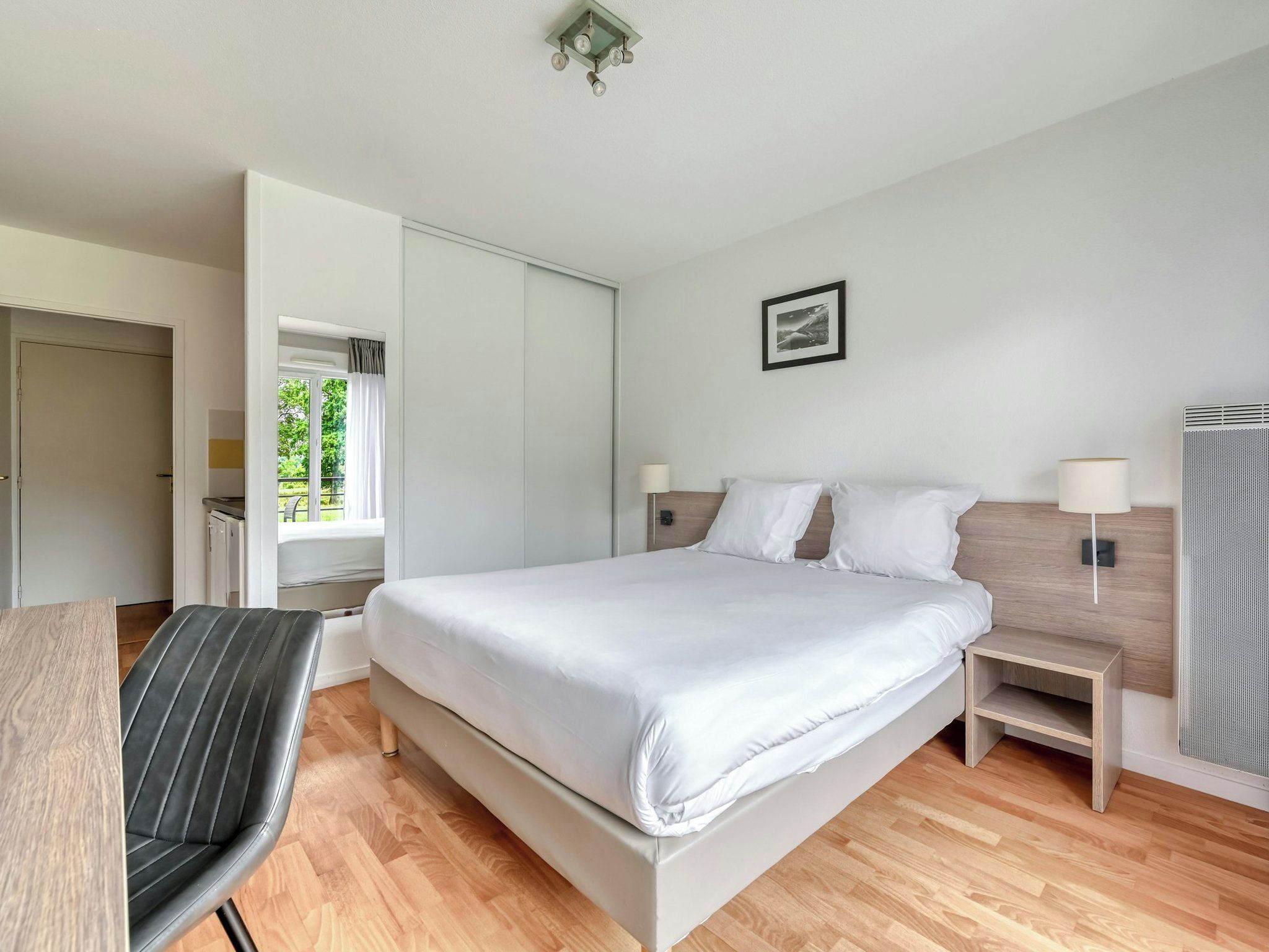 A modern bedroom with a bed, bedside tables, a chair, and a wardrobe.