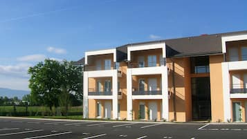 Een hotel met meerdere verdiepingen, balkons, een parkeerplaats en een heldere lucht.